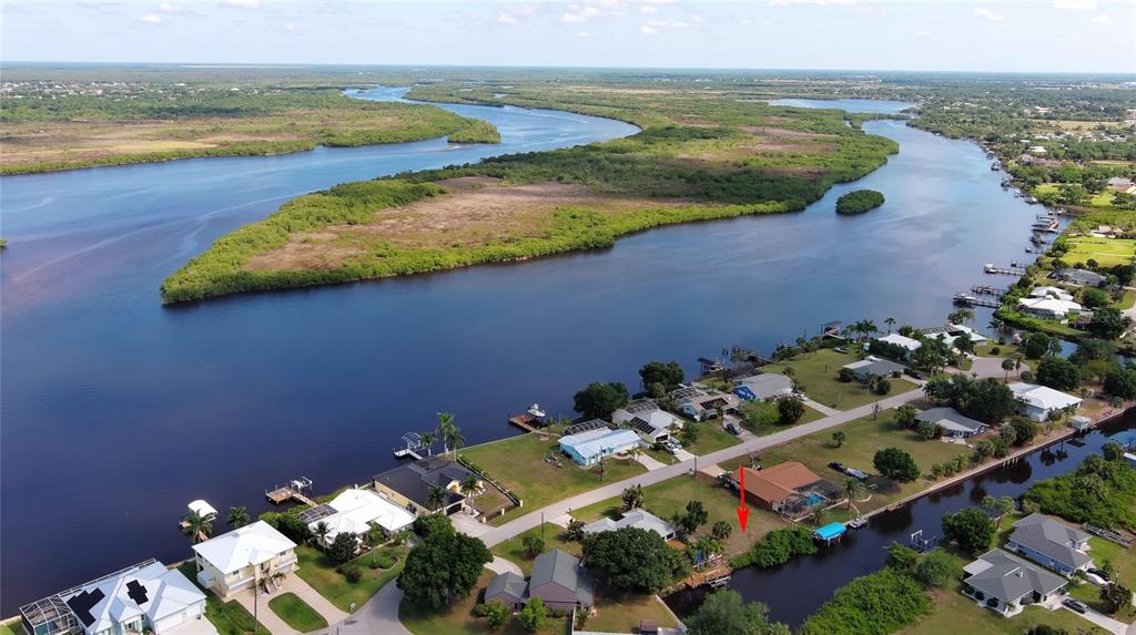 An aerial view shows a waterfront house with a red arrow pointing to its lot — 2060 RIVER BASIN TERRACE, PUNTA GORDA, FL