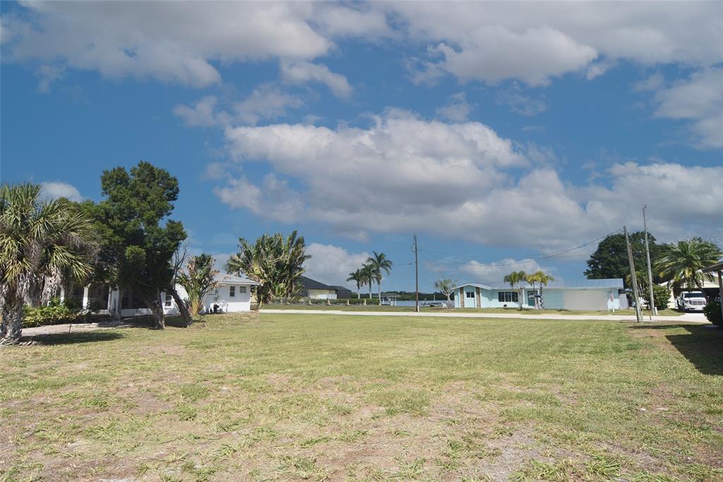 A vacant grassy lot sits between two houses with a view of the water beyond — 2060 RIVER BASIN TERRACE, PUNTA GORDA, FL