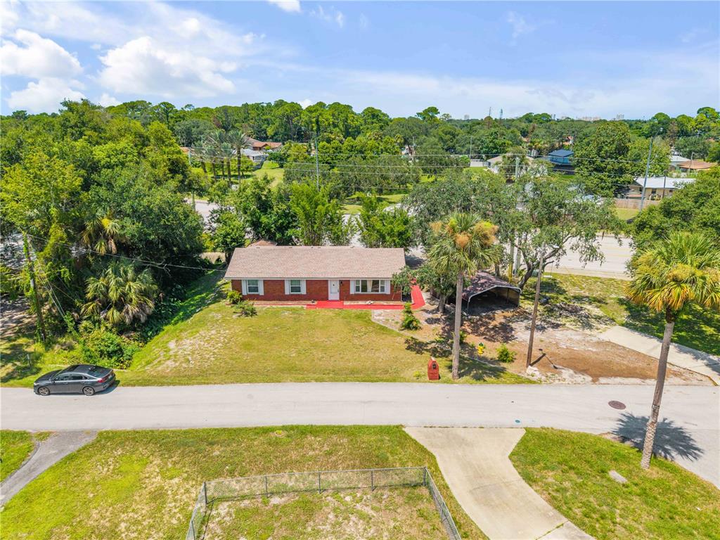 An aerial view shows a single-story brick house with a red porch and carport — 5680 PALM AVENUE, PORT ORANGE, FL
