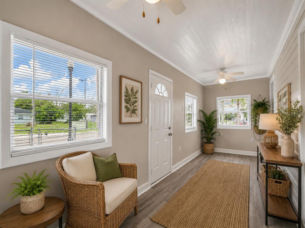 A sunroom features wicker furniture, a jute rug, wood-look flooring, and a white ceiling — 1101 DR MARTIN L KING JR WAY, HAINES CITY, FL