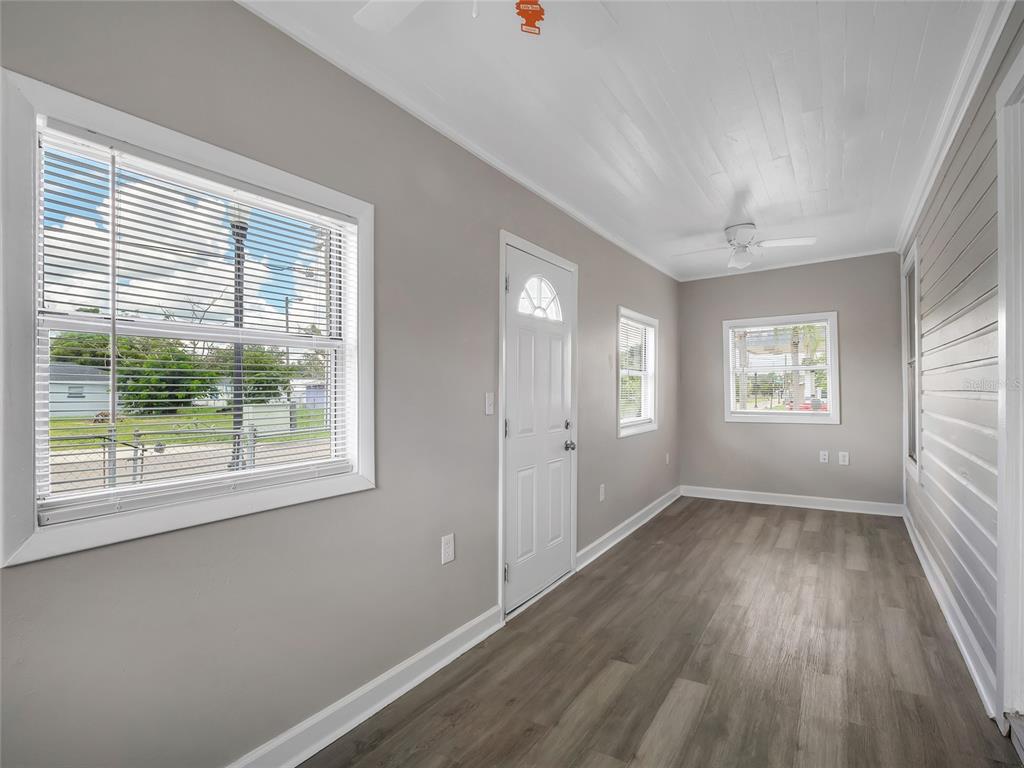 A sunroom with gray walls, wood-look flooring, a white ceiling, and several windows — 1101 DR MARTIN L KING JR WAY, HAINES CITY, FL