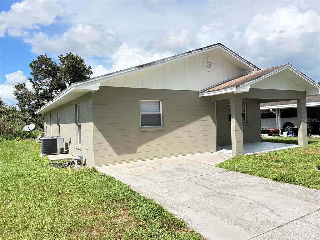 A single-story house with a tan block exterior, white siding, and a covered front porch — 1117 BLOSSOM CIRCLE N, LAKELAND, FL