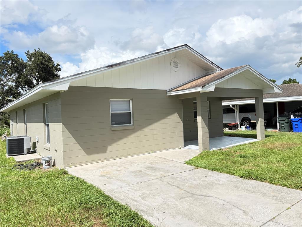 A single-story house with a tan concrete block exterior, white trim, and a covered front porch — 1117 BLOSSOM CIRCLE N, LAKELAND, FL