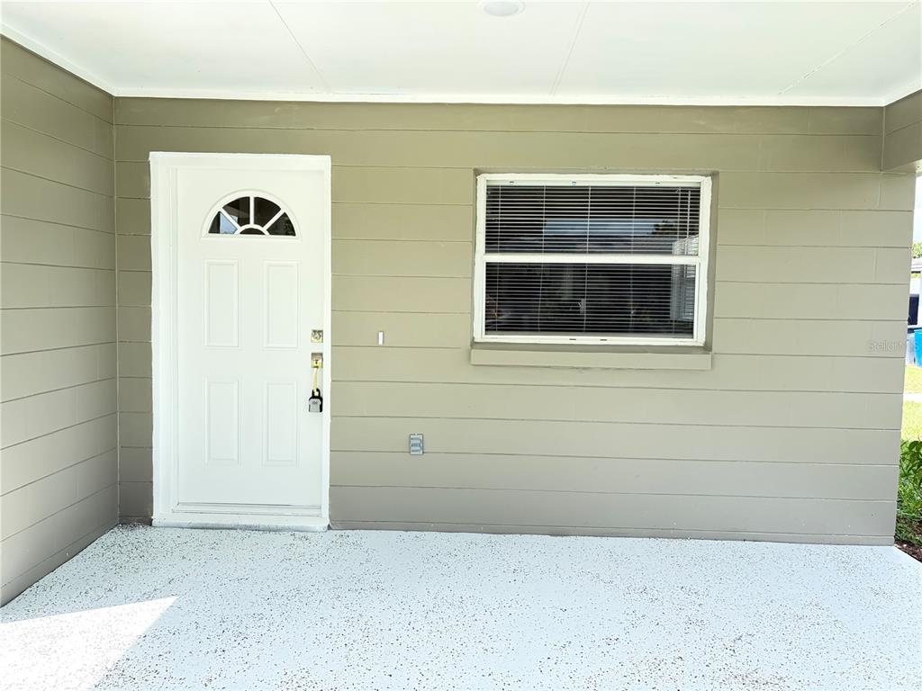 A white front door and a window with blinds on a light-colored exterior wall — 1117 BLOSSOM CIRCLE N, LAKELAND, FL