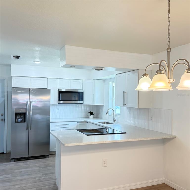 A kitchen with white cabinets, stainless steel appliances, and a peninsula countertop — 1117 BLOSSOM CIRCLE N, LAKELAND, FL