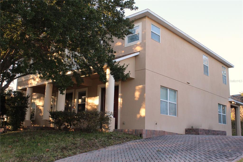 A two-story tan stucco house with a brick driveway and a covered front porch — 13019 SUMMERLAKE WAY, CLERMONT, FL