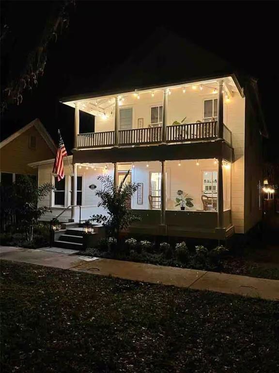 A two-story white house with a double-decker porch illuminated by string lights at night — 505 S MYRTLE AVENUE, SANFORD, FL