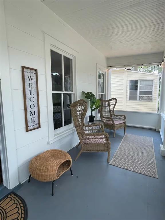 A covered porch features white siding, two wicker chairs, a small stool, and a rug — 505 S MYRTLE AVENUE, SANFORD, FL