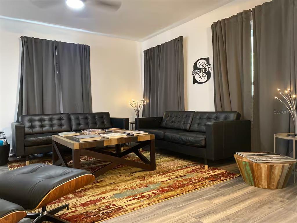 A living room features two black leather sofas, a wooden coffee table, and area rug — 505 S MYRTLE AVENUE, SANFORD, FL