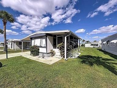 A single-story mobile home with a screened-in porch sits on a grassy lot — 213 LAKESIDE RANCH CIRCLE, WINTER HAVEN, FL