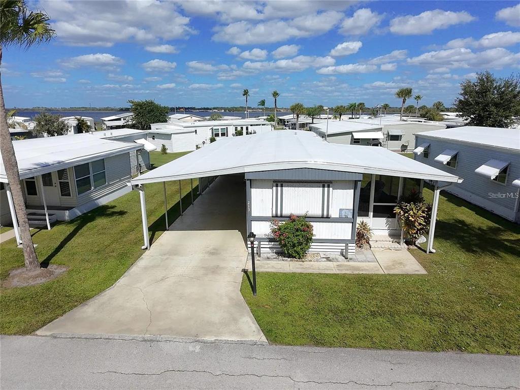 An elevated view of a manufactured home with a carport and a metal roof — 213 LAKESIDE RANCH CIRCLE, WINTER HAVEN, FL