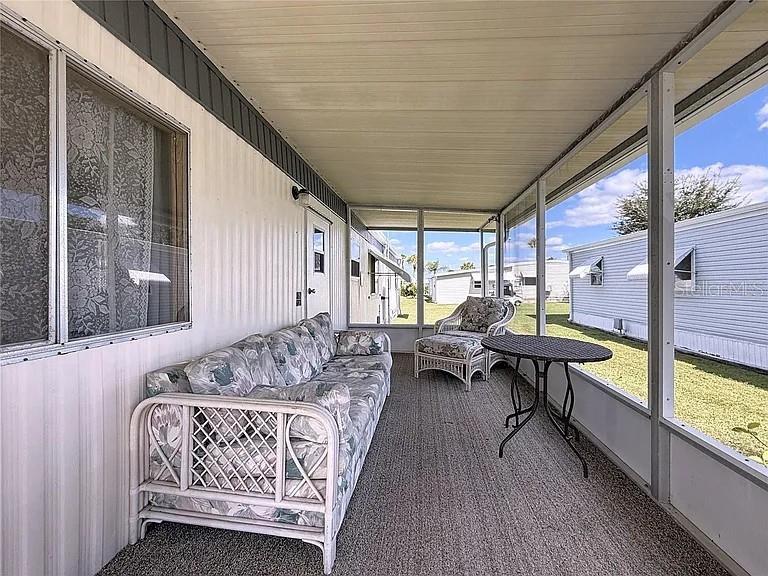 A screened-in porch features a floral sofa, a wicker chair, and a small round table — 213 LAKESIDE RANCH CIRCLE, WINTER HAVEN, FL