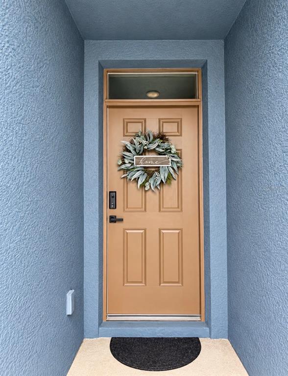 A brown front door with a wreath and transom window is set within a recessed entryway — 635 AUTUMN STREAM DRIVE, AUBURNDALE, FL
