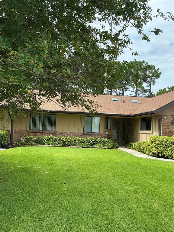 A single-story house with a brown shingled roof and tan siding sits behind a lawn — 31 LAKE FAIRGREEN CIRCLE, NEW SMYRNA BEACH, FL