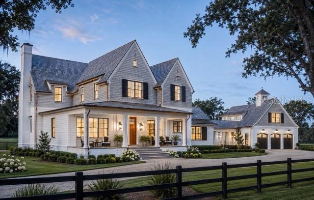 A two-story farmhouse with gray shingle siding, a wrap-around porch, and an attached three-car garage — Lot 2 SW 161 TERRACE, NEWBERRY, FL