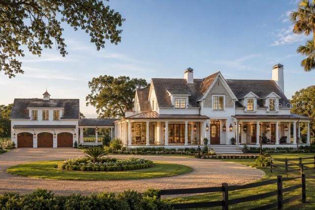 A white farmhouse with a wrap-around porch, detached garage, and a circular gravel driveway — Lot 2 SW 161 TERRACE, NEWBERRY, FL