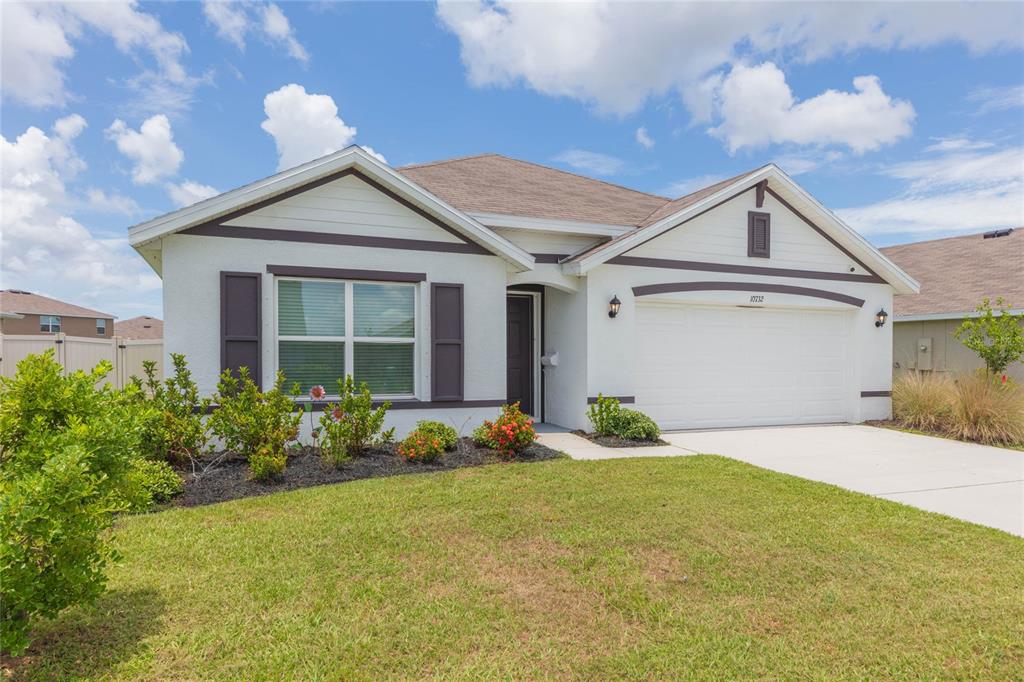 A single-story house with white stucco walls, a two-car garage, and a front lawn — 10732 CHIPPEWA DRIVE, PARRISH, FL