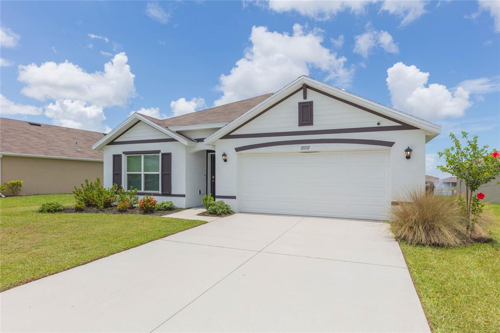 A single-story house with a white stucco exterior, dark trim, and a two-car garage — 10732 CHIPPEWA DRIVE, PARRISH, FL