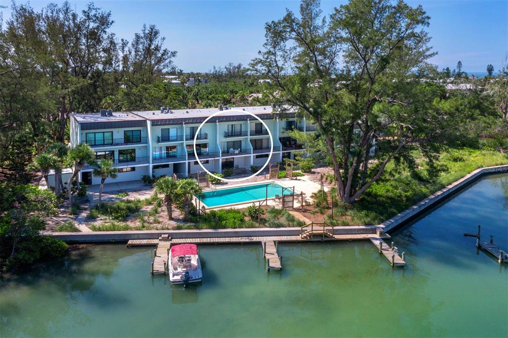 An aerial view of a waterfront condominium building with a pool and a private boat dock — 490 N SHORE ROAD UNIT 6, LONGBOAT KEY, FL