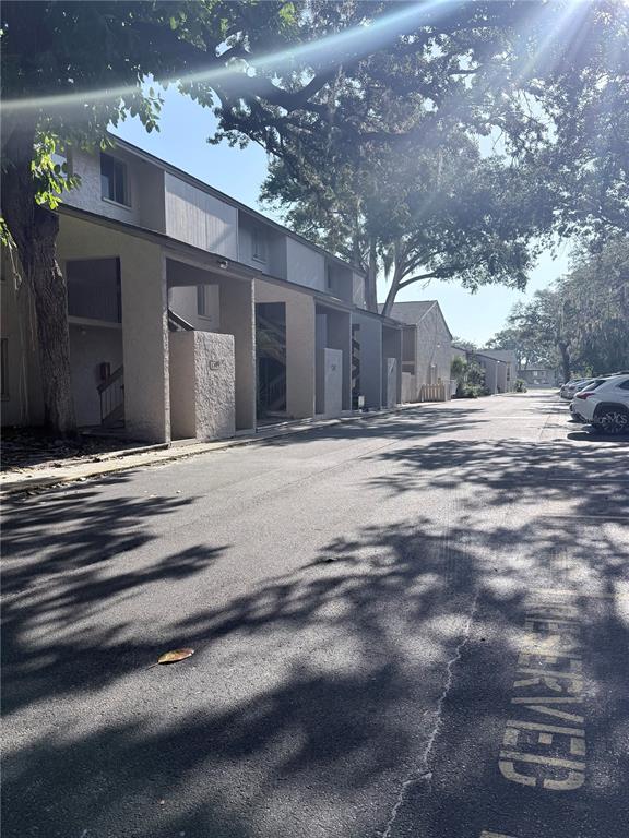 A multi-story apartment building exterior with covered entryways and a paved parking lot — 7509 PITCH PINE CIRCLE UNIT 121, TAMPA, FL