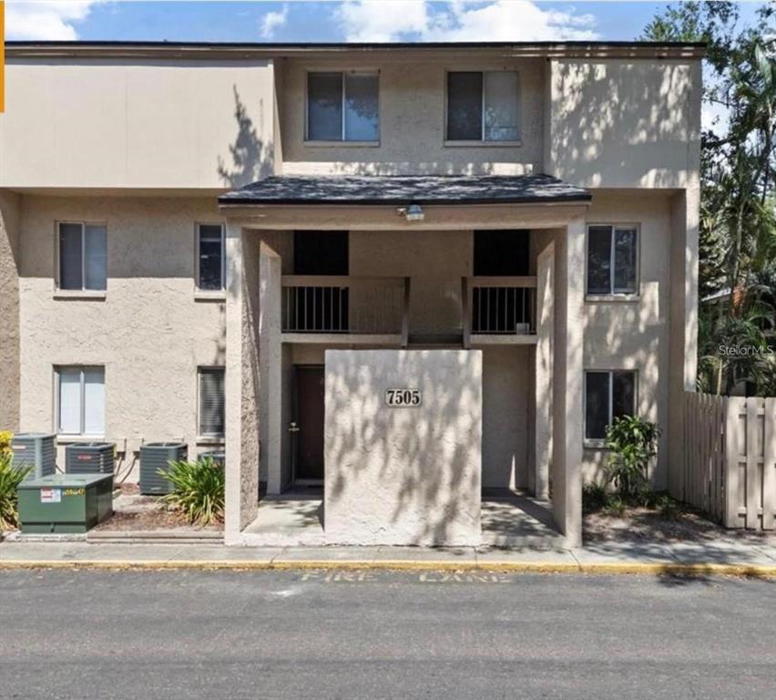 A two-story tan stucco apartment building with a central entrance and a fire lane — 7509 PITCH PINE CIRCLE UNIT 121, TAMPA, FL