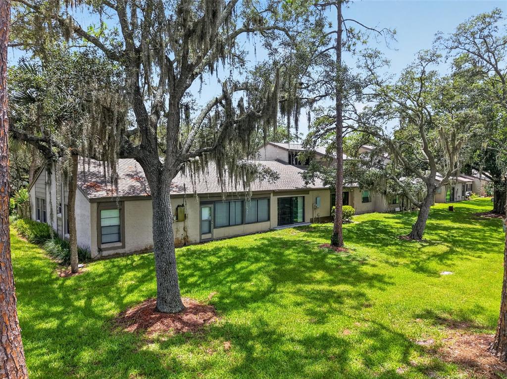 A multi-unit residential building with a shingled roof sits on a grassy lawn with trees — 612 WOODRIDGE DRIVE, CASSELBERRY, FL