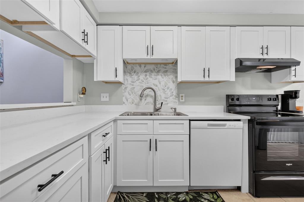 A kitchen features white shaker cabinets, white countertops, a patterned backsplash, and black appliances — 612 WOODRIDGE DRIVE, CASSELBERRY, FL