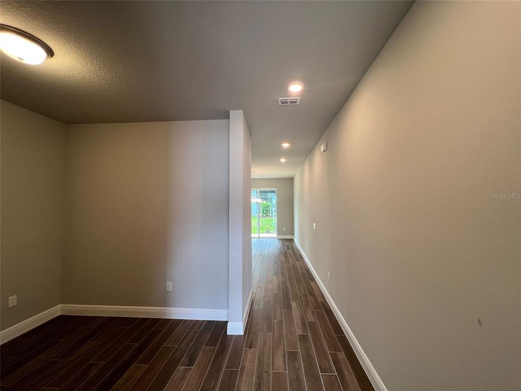 A hallway with wood-look tile flooring leads toward a glass sliding door — 1326 MERRYDALE WAY, WINTER PARK, FL