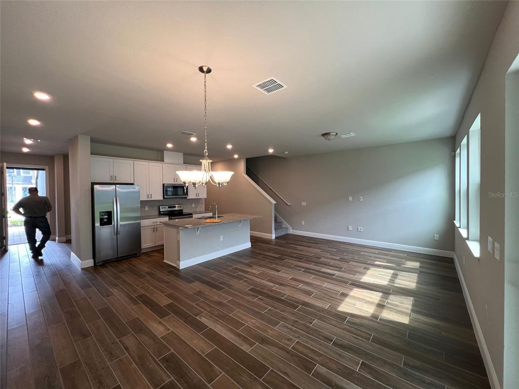 An open-concept kitchen and living area features wood-look tile flooring, white cabinetry, and a central island — 1326 MERRYDALE WAY, WINTER PARK, FL