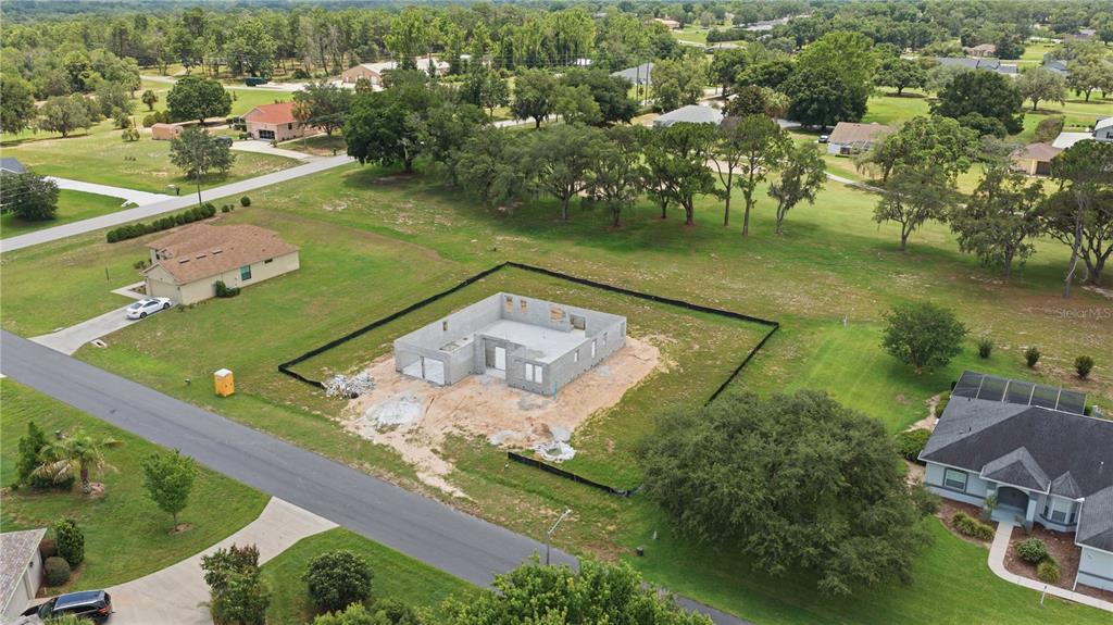 An aerial view shows a house under construction with a wooden roof frame and yard — 804 E EPSOM COURT, HERNANDO, FL