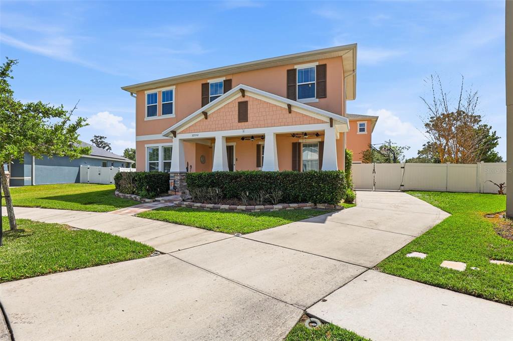 A two-story peach-colored house with a front porch, driveway, and manicured landscaping — 32550 RAPIDS LOOP, WESLEY CHAPEL, FL