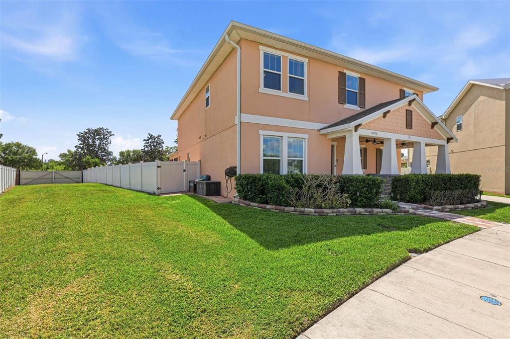 A two-story peach-colored house with a covered front porch and a white vinyl fence — 32550 RAPIDS LOOP, WESLEY CHAPEL, FL