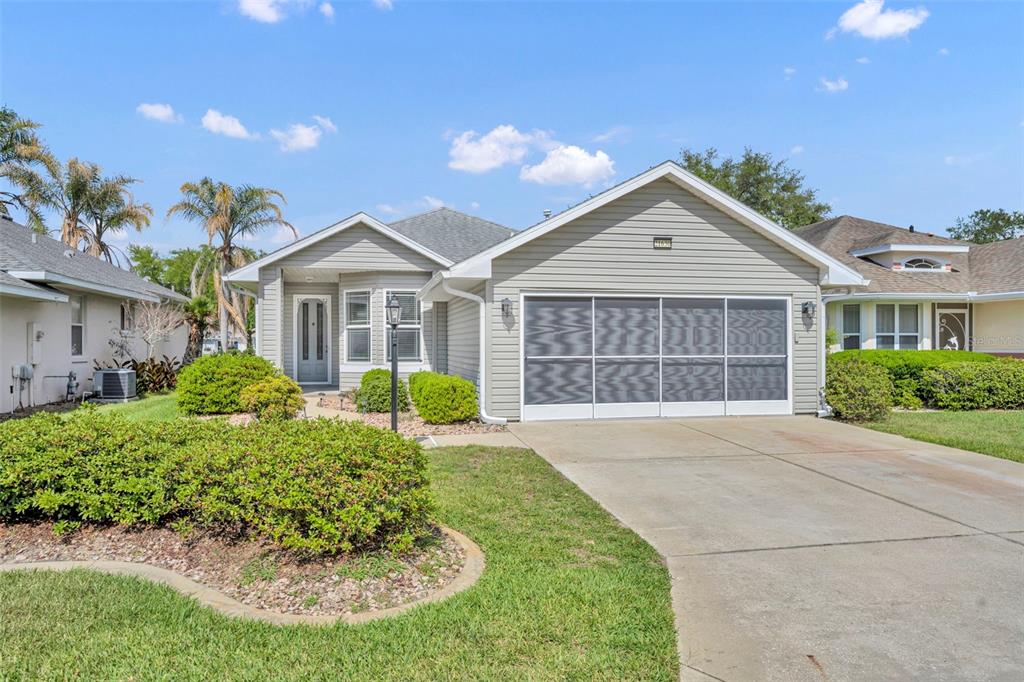 A virtually staged living and dining area with light wood floors and neutral furniture — 21630 REGENCY PARK LN, LEESBURG, FL