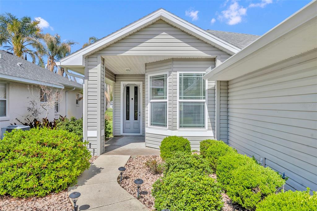 A sunroom features a rattan sectional, a matching armchair, and a glass door with privacy film — 21630 REGENCY PARK LN, LEESBURG, FL