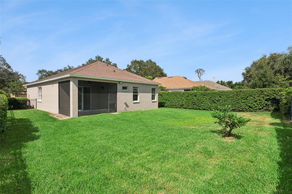 The backyard of a beige house features a screened-in patio and a manicured lawn — 1206 CHESSINGTON CIRCLE, LAKE MARY, FL