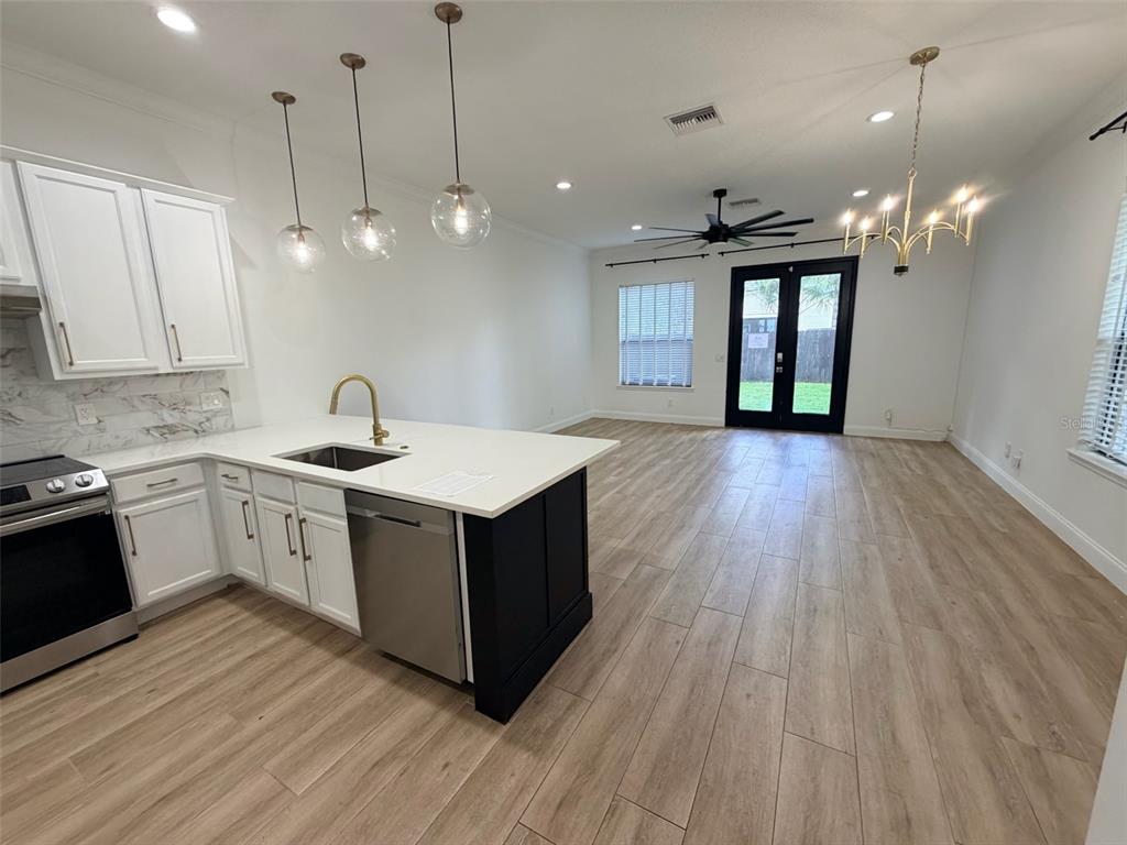 A kitchen with white cabinets and a dark island opens into a living area — 2013 E ESTHER STREET, ORLANDO, FL