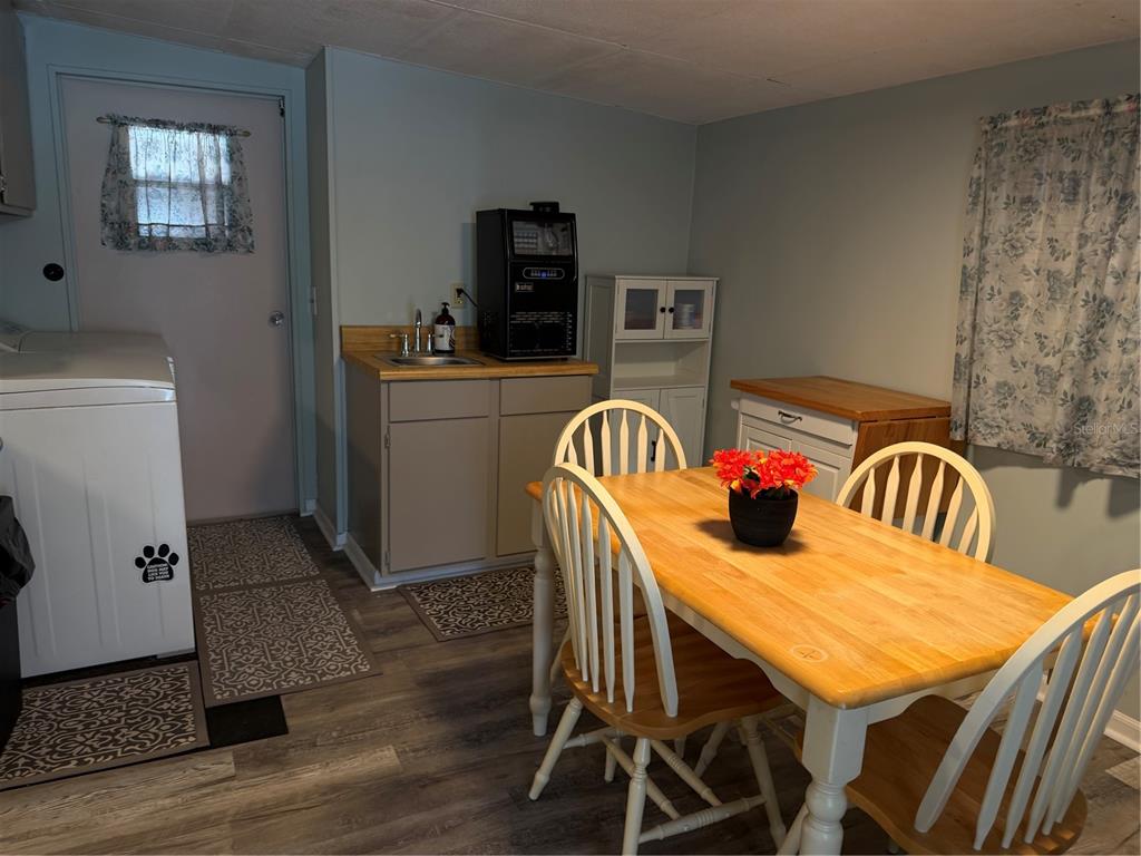 A dining area features a wooden table with chairs, a small sink, and a laundry appliance — 7175 FAIRLANE AVENUE, BROOKSVILLE, FL