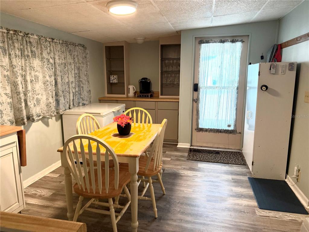 A dining area features a yellow table, four chairs, a chest freezer, and glass-front cabinets — 7175 FAIRLANE AVENUE, BROOKSVILLE, FL