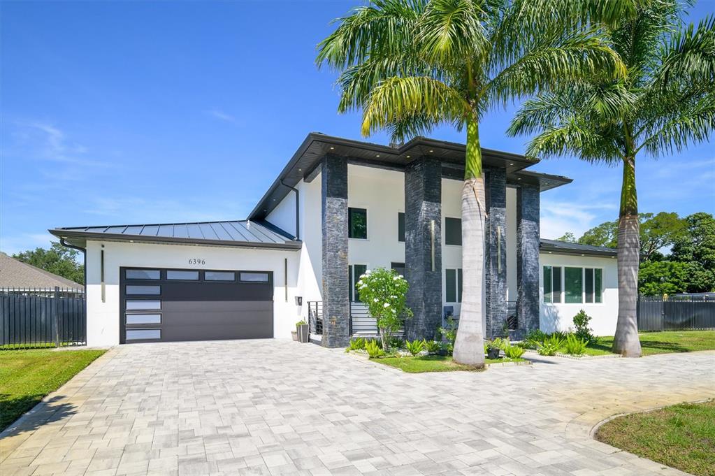 A modern two-story house features a stone facade, a dark garage, and two tall palm trees — 6396 18TH STREET N, ST PETERSBURG, FL