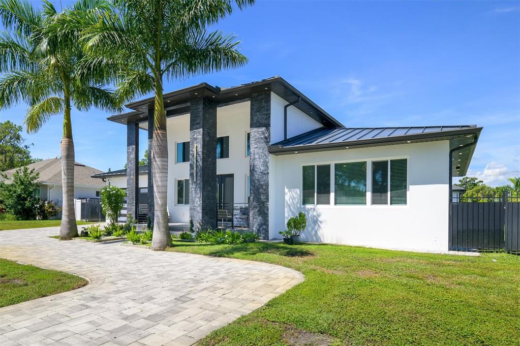 A modern house with white stucco walls, dark stone accents, and a paved driveway — 6396 18TH STREET N, ST PETERSBURG, FL