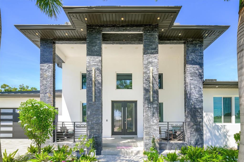 The exterior of a modern home features a stone-clad entryway with a large roof overhang — 6396 18TH STREET N, ST PETERSBURG, FL