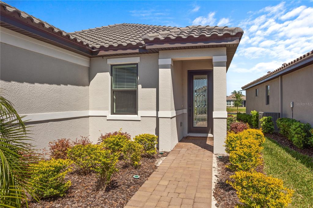 A paved walkway leads to the front entrance of a house with a tiled roof — 4724 CRESTPOINT WAY, PALMETTO, FL