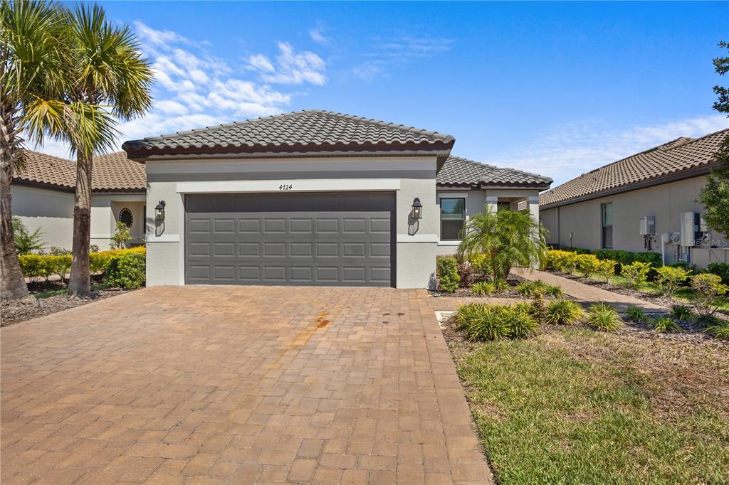 A single-story house with a gray garage door, tile roof, and a paved driveway — 4724 CRESTPOINT WAY, PALMETTO, FL