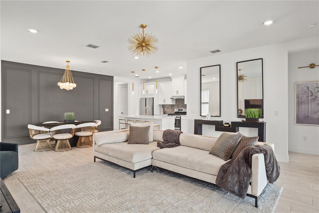 An open-concept living and dining area features a sectional sofa, modern lighting, and dark accents — 4724 CRESTPOINT WAY, PALMETTO, FL