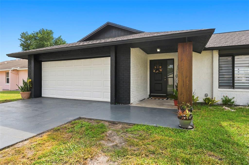 A single-story house with a white brick facade, black trim, a garage, and a covered entryway — 10500 RAMBLEWOOD ROAD, ORLANDO, FL