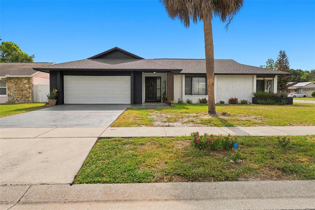 A single-story house with a white brick exterior, black trim, and a two-car garage — 10500 RAMBLEWOOD ROAD, ORLANDO, FL