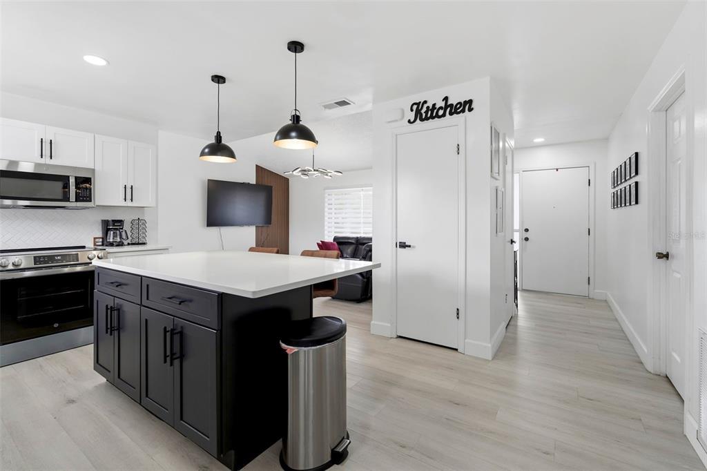 A kitchen features a dark island with a white countertop, white cabinets, and light flooring — 10500 RAMBLEWOOD ROAD, ORLANDO, FL