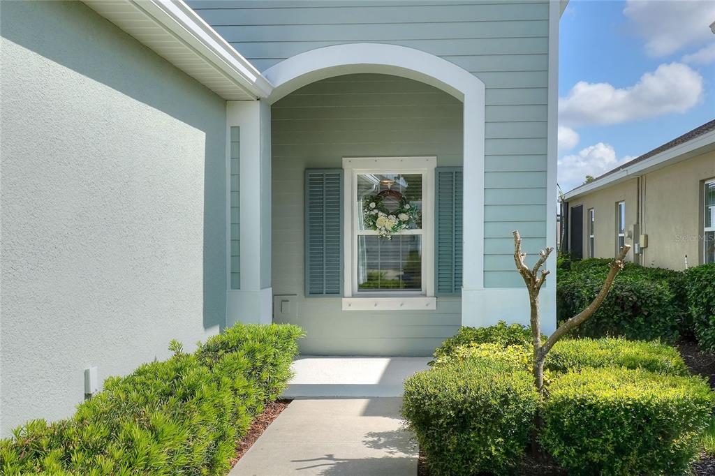 A light blue house exterior features a covered entryway with a window and green shutters — 13529 CIRCA CROSSING DRIVE, LITHIA, FL