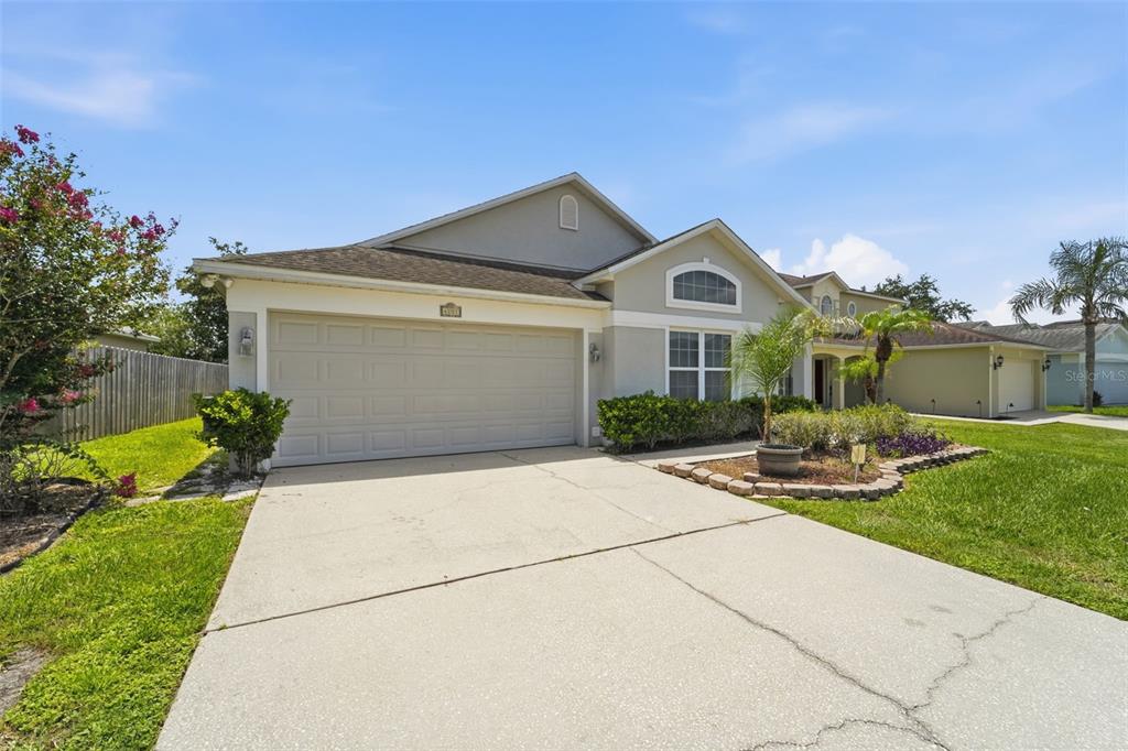 A single-story suburban house with a two-car garage, concrete driveway, and landscaped front yard — 4201 PACIFICA DRIVE, ORLANDO, FL