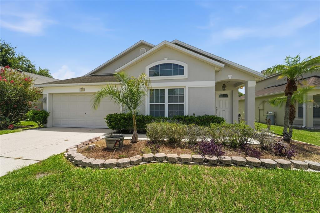 A single-story house with a beige exterior, a two-car garage, and a landscaped front yard — 4201 PACIFICA DRIVE, ORLANDO, FL